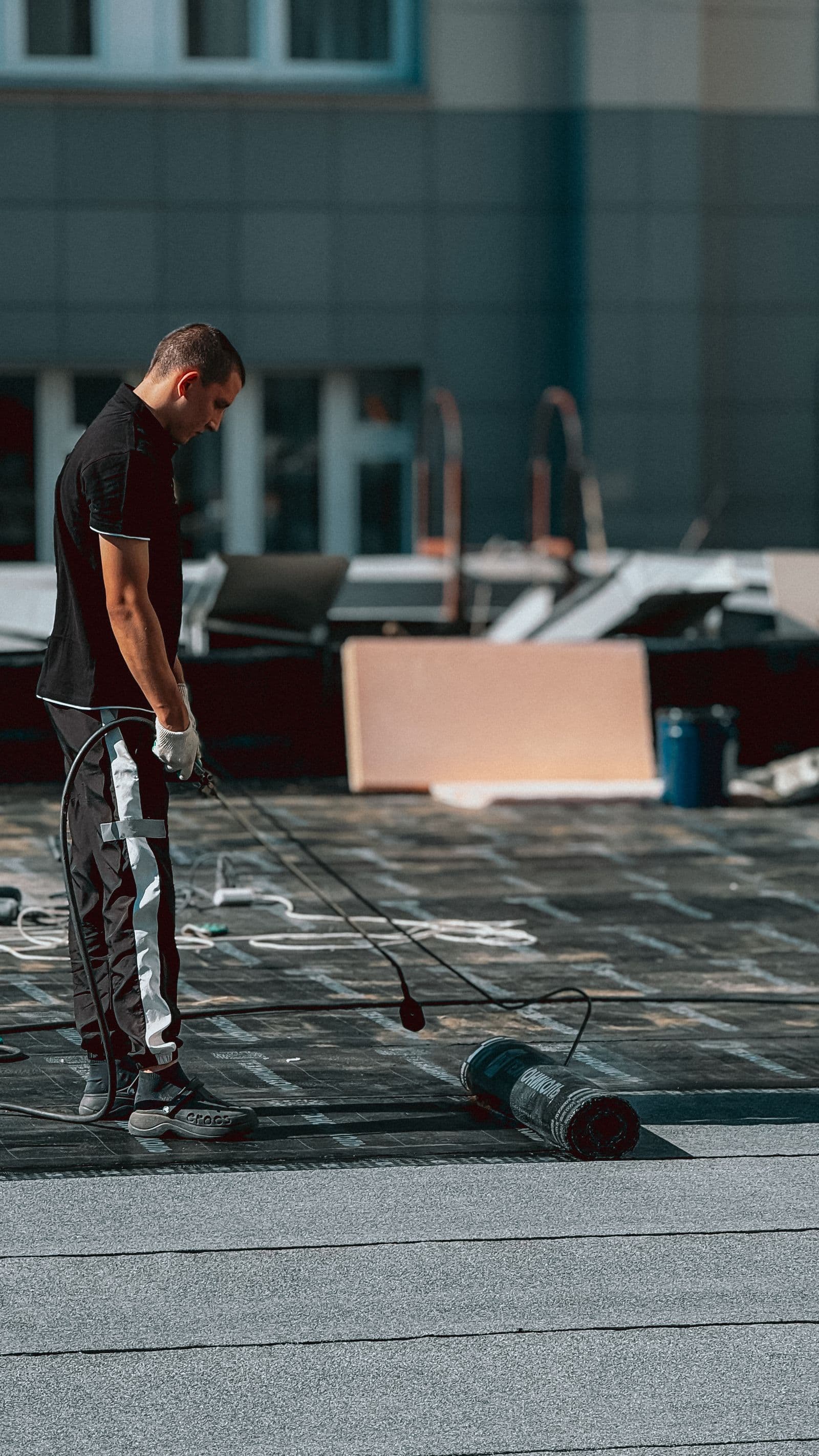 Flat commercial rooftop with plant equipment and a worker preparing the deck