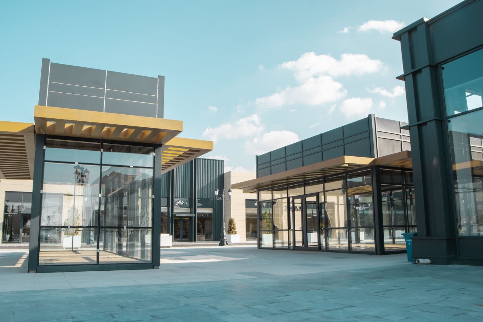 Modern retail plaza with glass storefronts under a clear sky