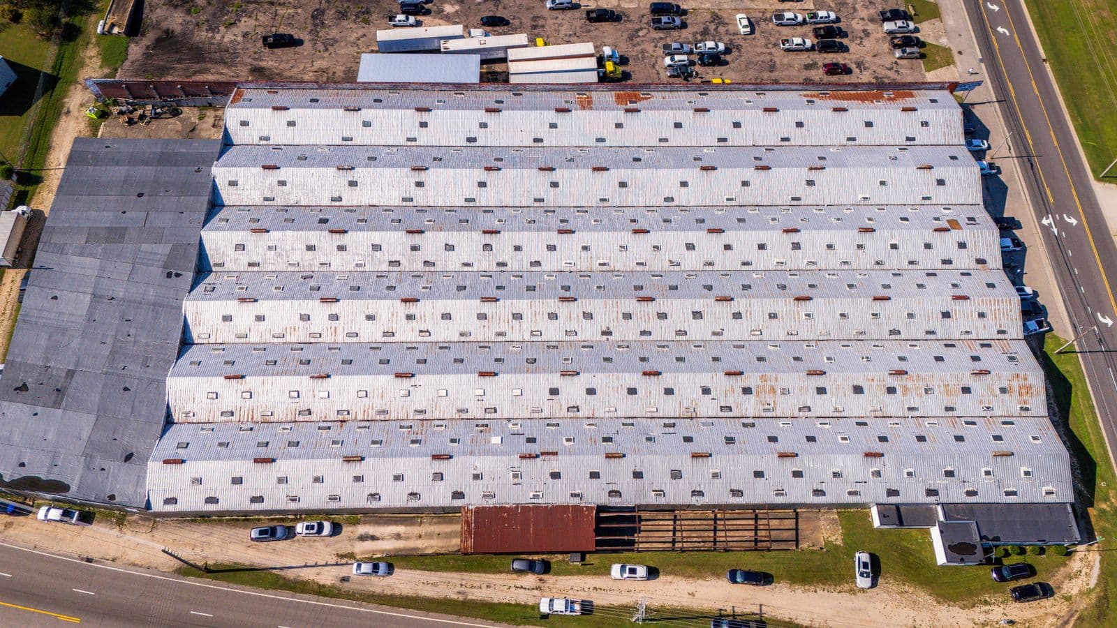 Aerial view of a large distribution warehouse with a vast ribbed metal roof and loading docks