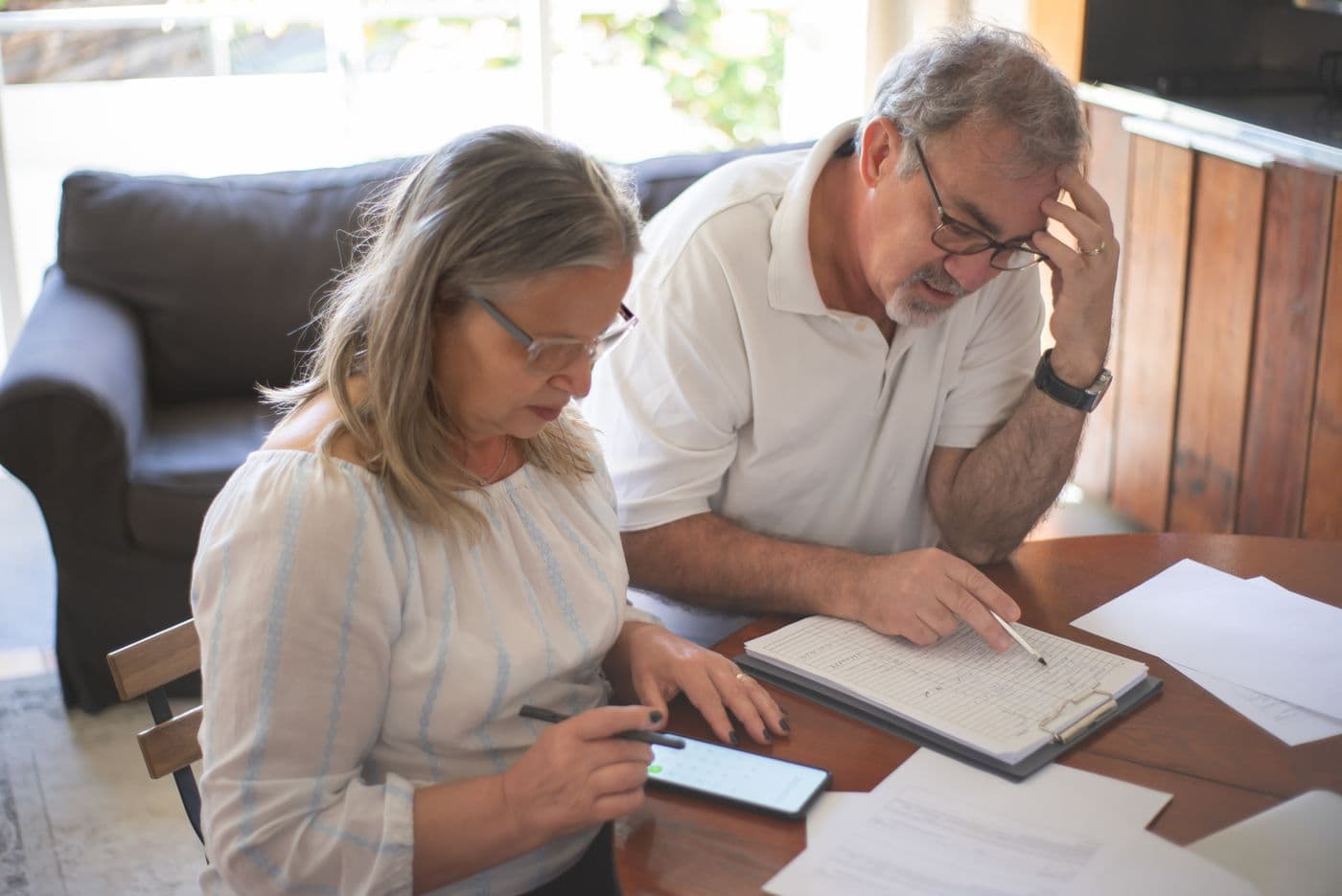 Two people at a kitchen table going through paperwork and planning a household budget
