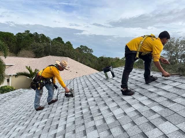 Two Roofing Direct crew members in harnesses repairing a shingle roof
