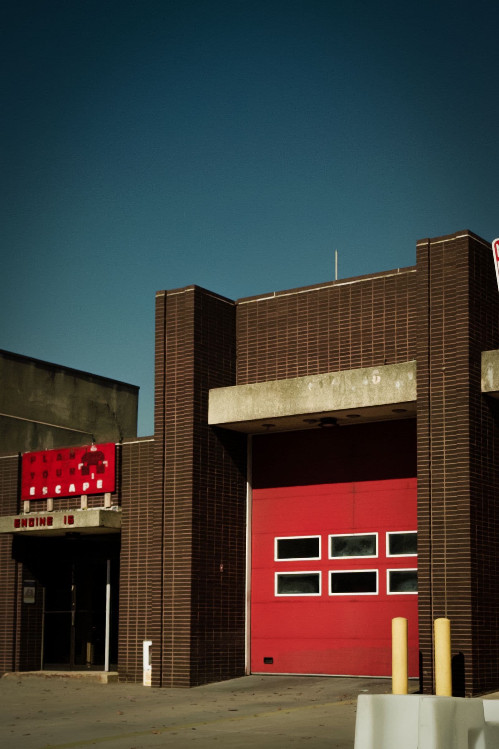 Modern fire station with a red apparatus bay door under a clear sky