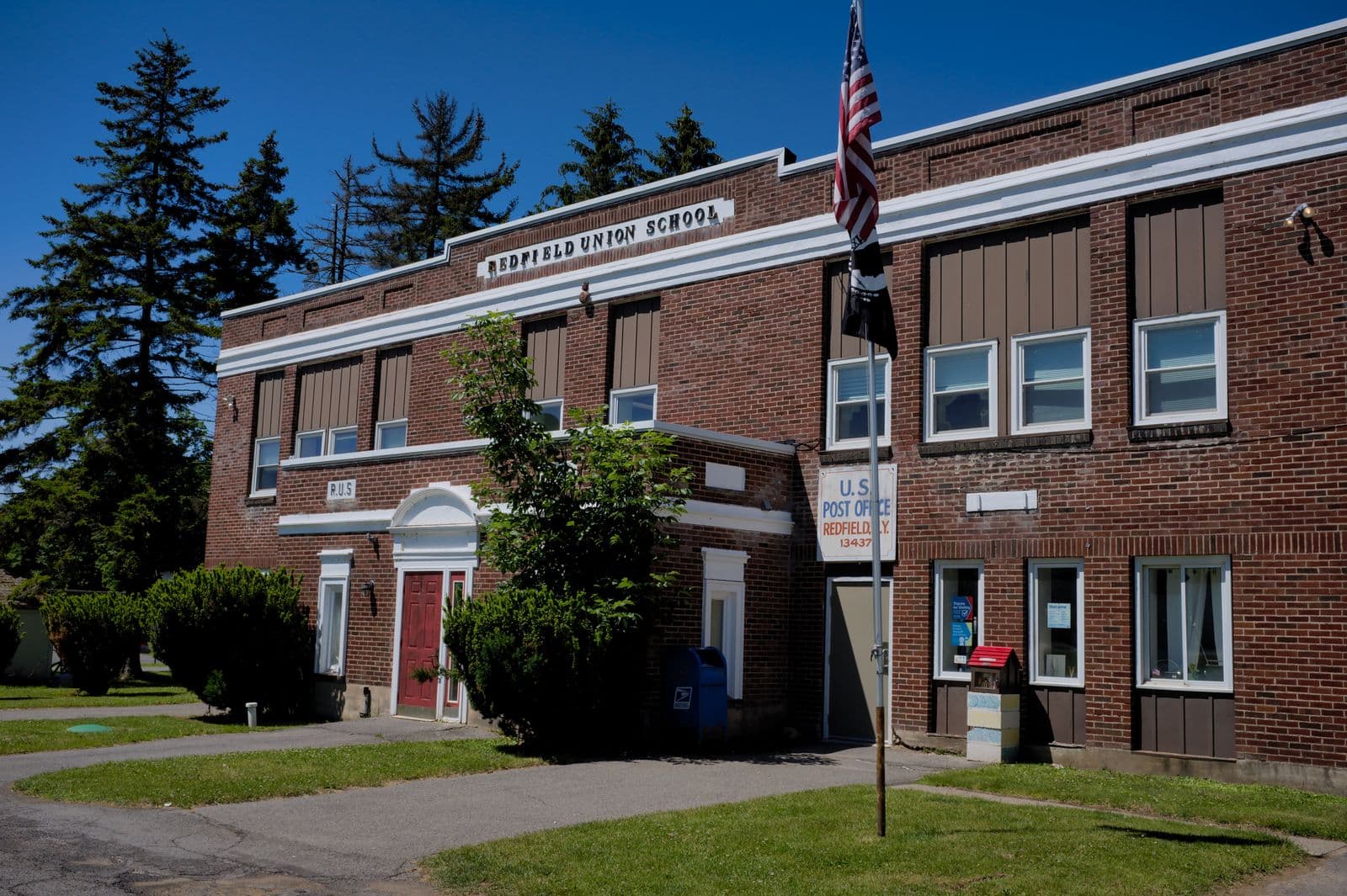 Brick American public school building with a US flag flying beside the entrance