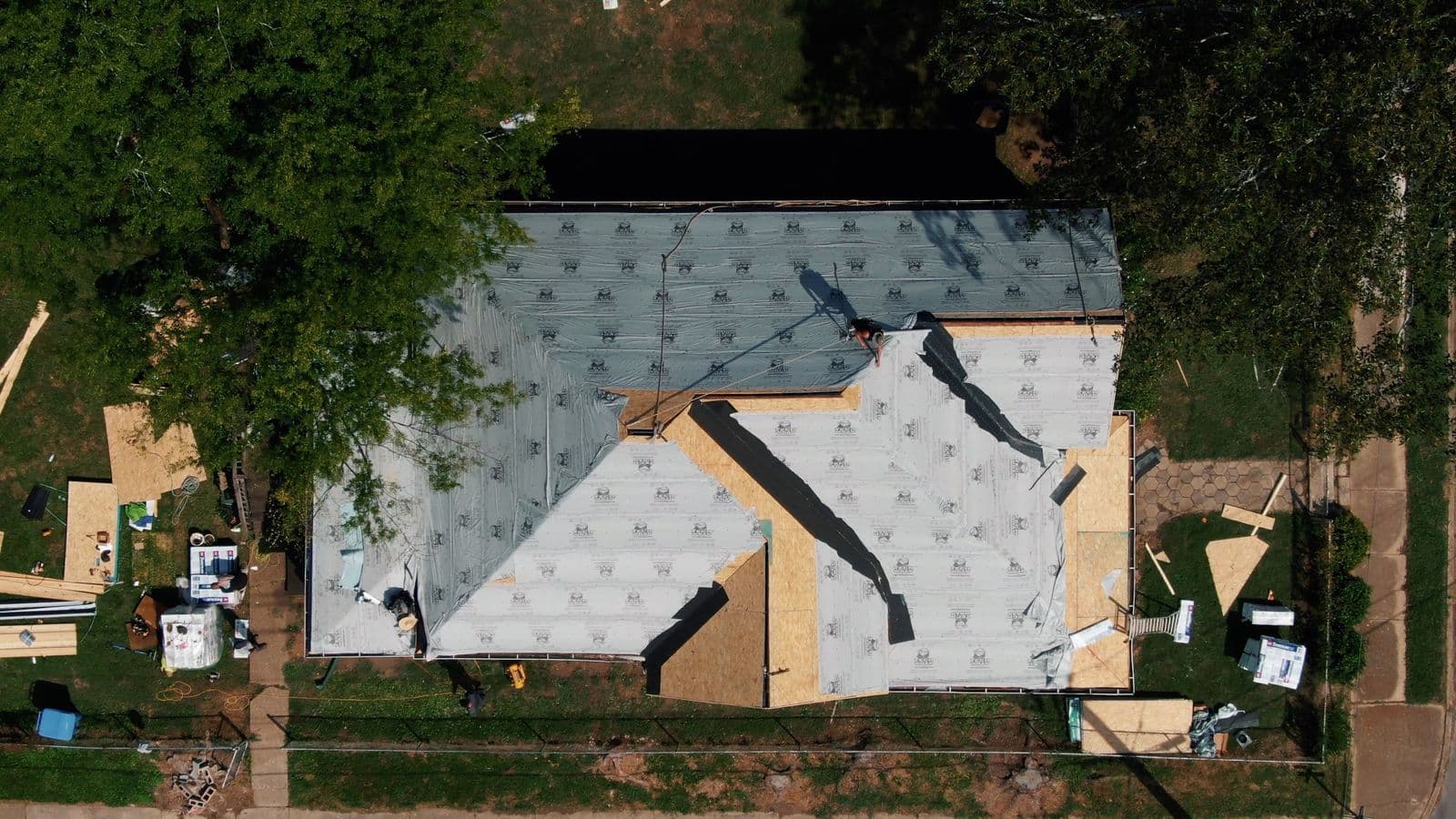 Aerial view of a house roof dried in with fresh underlayment after storm damage